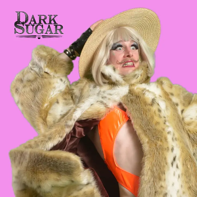 dark sugar drag queen wearing fur coat and beach hat